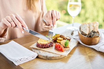 Lunch in a restaurant, a woman eats roasted octopus BBQ with Baked potato. Wooden plate. Restaurant menu