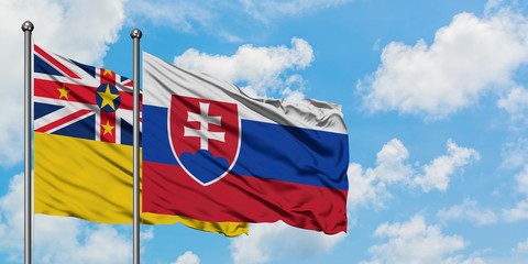 Niue and Slovakia flag waving in the wind against white cloudy blue sky together. Diplomacy...