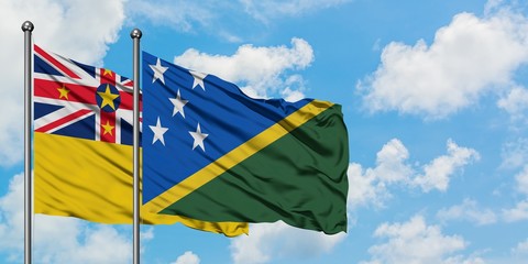 Niue and Solomon Islands flag waving in the wind against white cloudy blue sky together. Diplomacy concept, international relations.