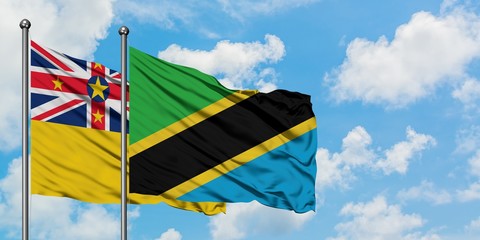 Niue and Tanzania flag waving in the wind against white cloudy blue sky together. Diplomacy concept, international relations.