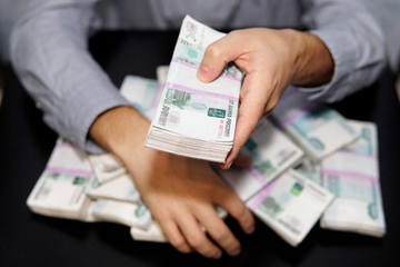 men's hands reach for wad of money. A million rubles on the black table. The concept of wealth,...