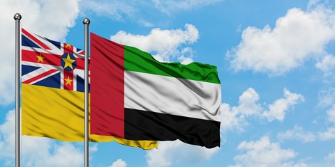 Niue and United Arab Emirates flag waving in the wind against white cloudy blue sky together. Diplomacy concept, international relations.