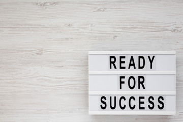 'Ready for success' words on a modern board on a white wooden background, top view. Overhead, from above, flat lay. Space for text.