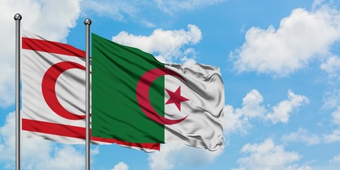 Northern Cyprus and Algeria flag waving in the wind against white cloudy blue sky together....