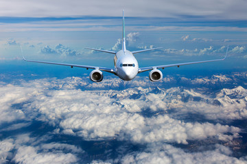 Passenger plane in flight. The plane flies above a snow covered mountain landscape. Aircraft front...