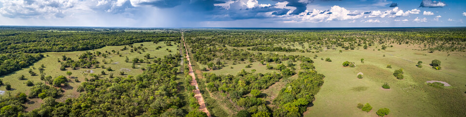 Aerial view panorama of typical Pantanal landscape with Transpantaneira, meadows, forest, pasture and dramatic sky, Pantanal Wetlands, Mato Grosso, Brazil - obrazy, fototapety, plakaty