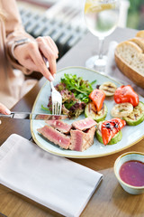 Lunch in a restaurant, a woman eats Medium rare tuna with lettuce and hot sauce. Restaurant menu