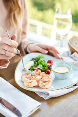 Grilled Argentine shrimp with mango-jalapeno sauce. Lunch in a restaurant, a woman eats delicious and healthy food. Delicious fresh seafood prawns with fresh vegetables and lime. Cream sauce