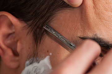 Macro photo man is shaving beard. Beard shaving procedure.Foam and shaver