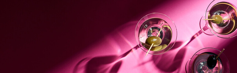 Top view of martini cocktails on bright pink background with shadows, panoramic shot