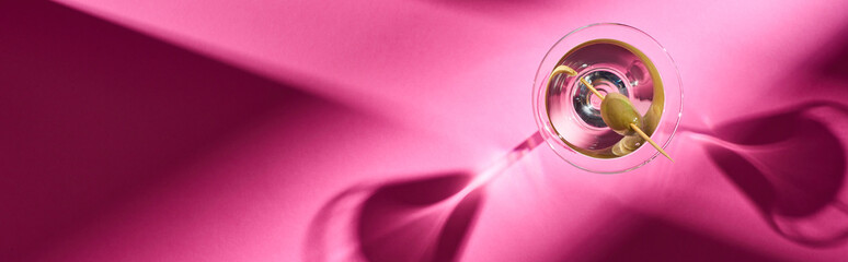 Top view of martini cocktail with shadows and copy space on pink background