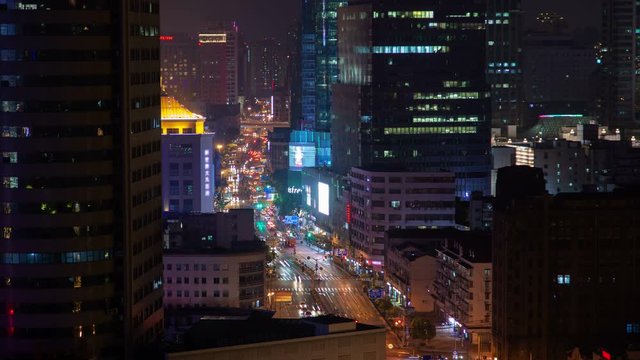 Timelapse autos in heavy traffic on Shanghai road between illuminated Chinese highrise buildings with flashing advertisement lights at night on July 12 in Shanghai