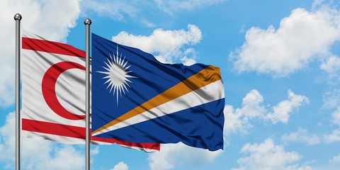 Northern Cyprus and Marshall Islands flag waving in the wind against white cloudy blue sky together. Diplomacy concept, international relations.