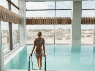 Girl relaxing in luxury swimming pool in modern hotel