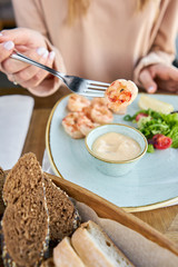 Grilled Argentine shrimp with mango-jalapeno sauce. Lunch in a restaurant, a woman eats delicious and healthy food. Delicious fresh seafood prawns with fresh vegetables and lime. Cream sauce