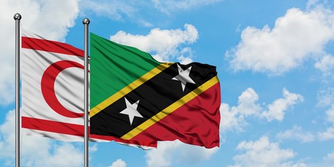 Northern Cyprus and Saint Kitts And Nevis flag waving in the wind against white cloudy blue sky...