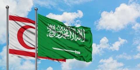Northern Cyprus and Saudi Arabia flag waving in the wind against white cloudy blue sky together....