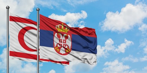 Northern Cyprus and Serbia flag waving in the wind against white cloudy blue sky together....