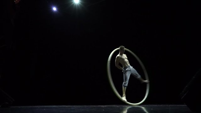 Muscular circus artist in the Cyr Wheel doing difficult tricks slow motion. Concept of concentration and balance