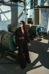 Fototapeta na wymiar stylish elegant woman posing in trendy burgundy suit and sunglasses on urban roof