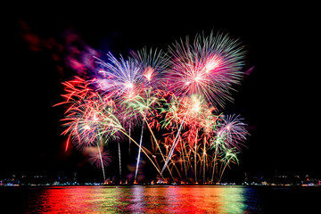 Amazing beautiful colorful fireworks display on celebration night, showing on the sea beach with multi color of reflection on water