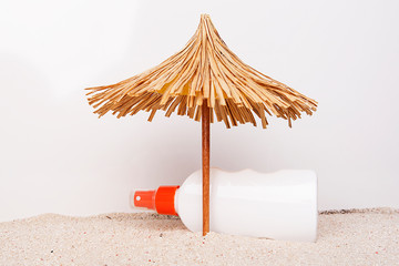 Toy sun umbrella on sandy beach at the white background. Relaxation concept.