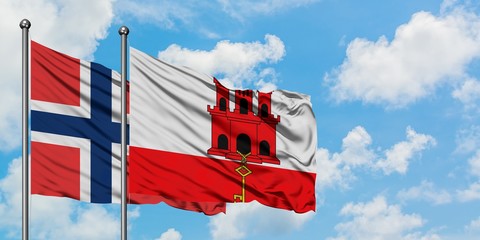 Norway and Gibraltar flag waving in the wind against white cloudy blue sky together. Diplomacy concept, international relations.