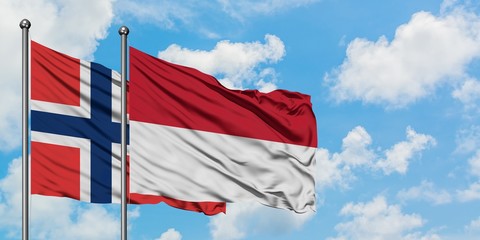 Norway and Indonesia flag waving in the wind against white cloudy blue sky together. Diplomacy concept, international relations.