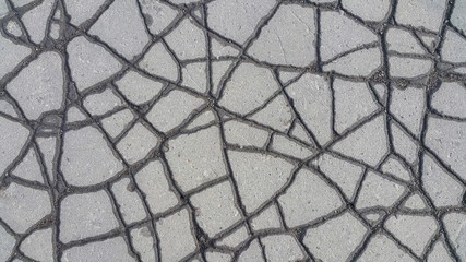 cracked asphalt after rain, near cracks asphalt wet, and middle of the dry, in a result is obtained the beautiful background texture, a similar on lines highways from above.