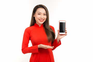 Naklejka premium Attractive woman in ao dai dress showing screen mobile phone, isolated on white background