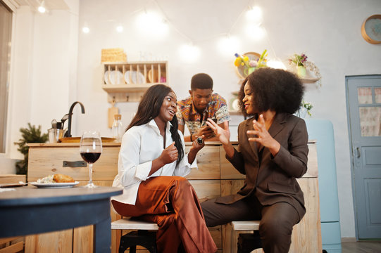Three african american friends spending time at kitchen with wine. Black peoples relaxing at home. - Powered by Adobe