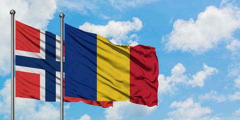 Norway and Romania flag waving in the wind against white cloudy blue sky together. Diplomacy...