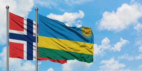 Norway and Rwanda flag waving in the wind against white cloudy blue sky together. Diplomacy...