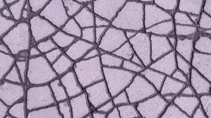 cracked asphalt after rain, near cracks asphalt wet, and middle of the dry, in a result is obtained the beautiful background texture a similar on lines highways from above. Pink style