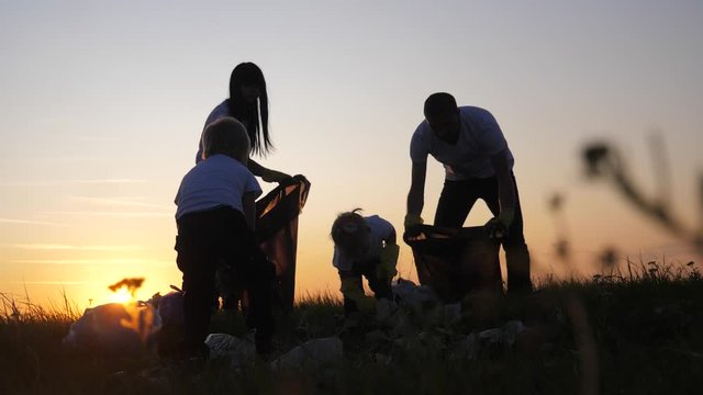 environmental teamwork a ecology teamwork volunteers awareness pollution household waste concept. people group happy family silhouette on the sunset collects garbage plastic and paper waste bottles