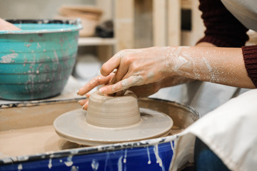 Sculptor woman makes a cup on a potters wheel.