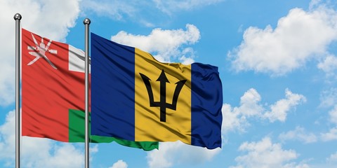 Oman and Barbados flag waving in the wind against white cloudy blue sky together. Diplomacy concept, international relations.