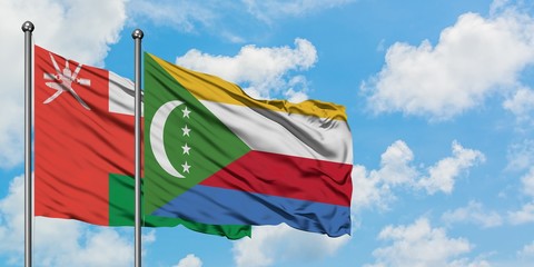 Oman and Comoros flag waving in the wind against white cloudy blue sky together. Diplomacy concept,...