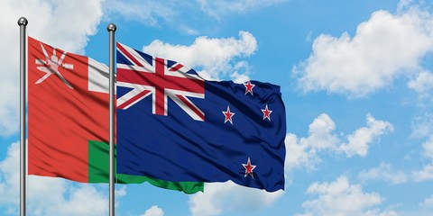 Oman and New Zealand flag waving in the wind against white cloudy blue sky together. Diplomacy...