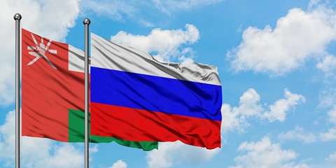 Oman and Russia flag waving in the wind against white cloudy blue sky together. Diplomacy concept,...