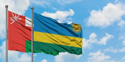 Oman and Rwanda flag waving in the wind against white cloudy blue sky together. Diplomacy concept, international relations.