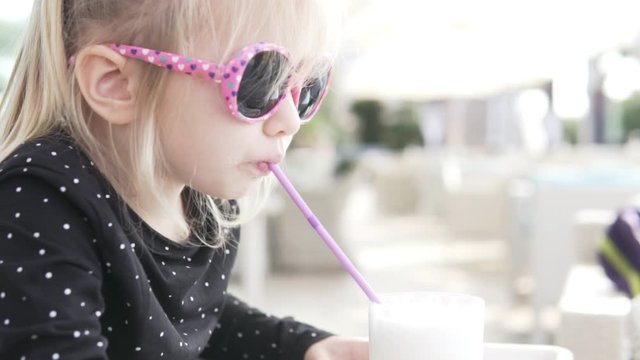 child in sunglasses drinks a milkshake