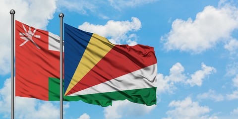 Oman and Seychelles flag waving in the wind against white cloudy blue sky together. Diplomacy...