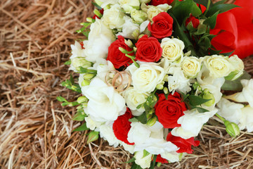 top view of luxury bouquet of red and white flowers on hay top view with red bow on wedding day holiday