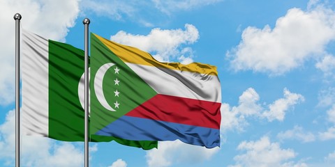 Pakistan and Comoros flag waving in the wind against white cloudy blue sky together. Diplomacy...