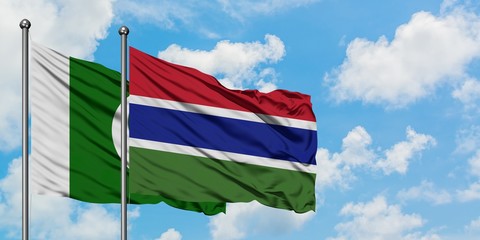 Pakistan and Gambia flag waving in the wind against white cloudy blue sky together. Diplomacy...