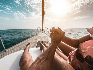 Senior couple having tender moments while traveling with sailboat - Husband and wife enjoying wood yach boat during sunny day on atlantic ocean - Travel and joyful elderly lifestyle - Focus on hands