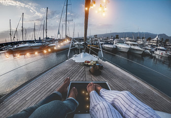 Legs view of senior couple having holidays on sail vintage boat - 60's trendy people enjoying a...