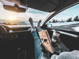 Woman drinking coffee paper cup inside car with feet warm socks on dashboard - Girl relaxing in...