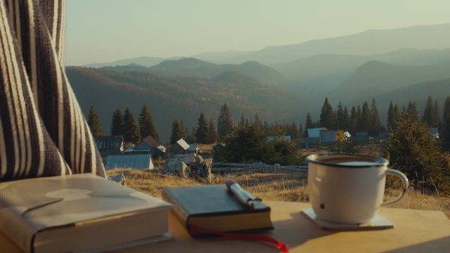 Van life, steaming coffee and notebooks before mountain range panorama view outside the car at dusk, SLOW PAN AND SLIDE